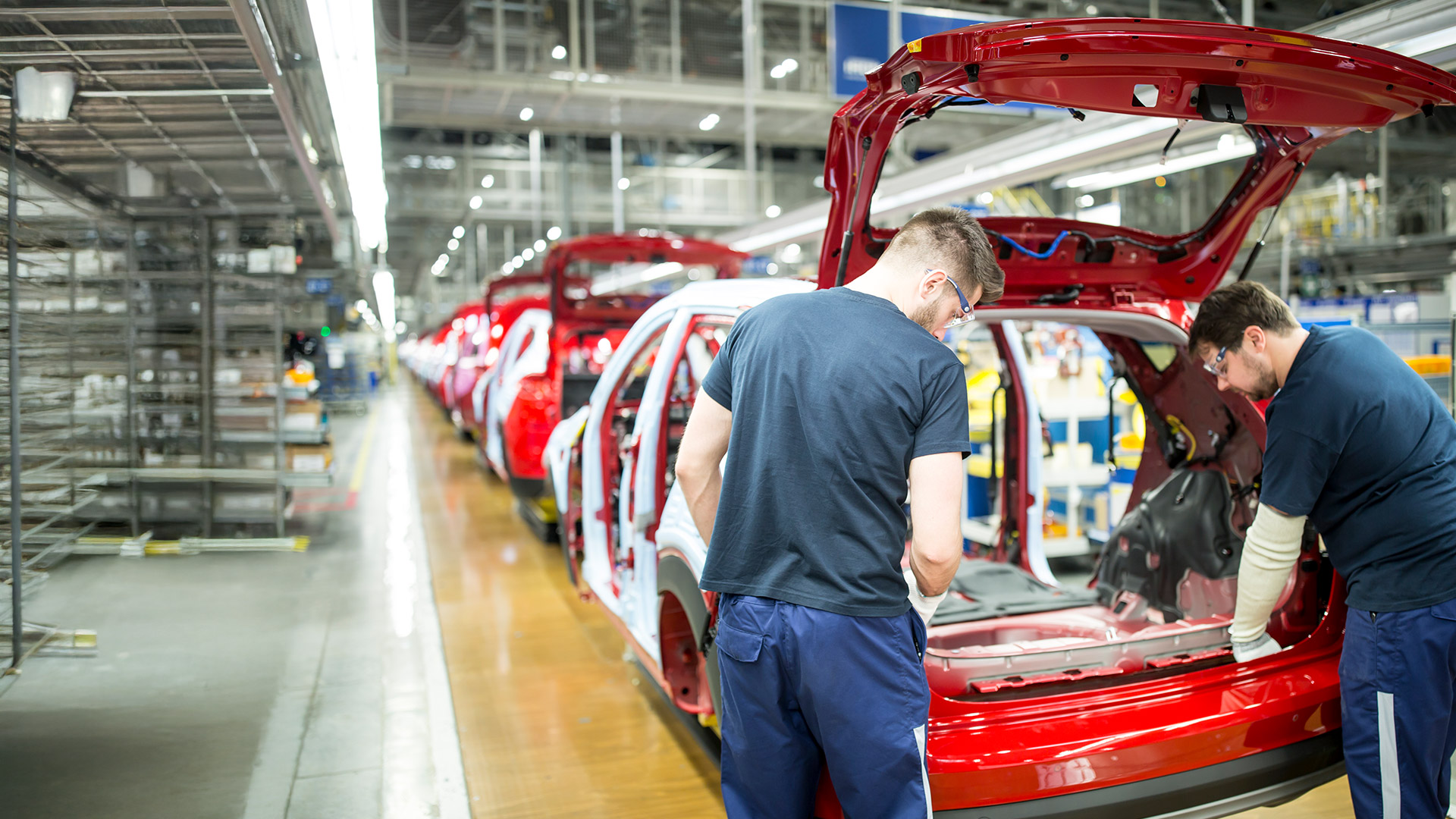 Mężczyżni na lini produkcyjnej aut osobowych.