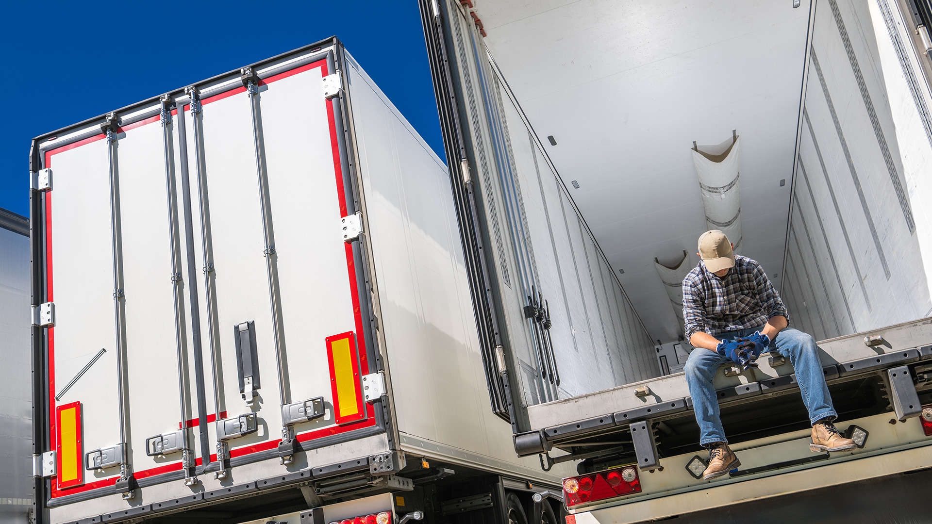 Mężczyzna siedzący na otwartej naczepie ciężarówki.