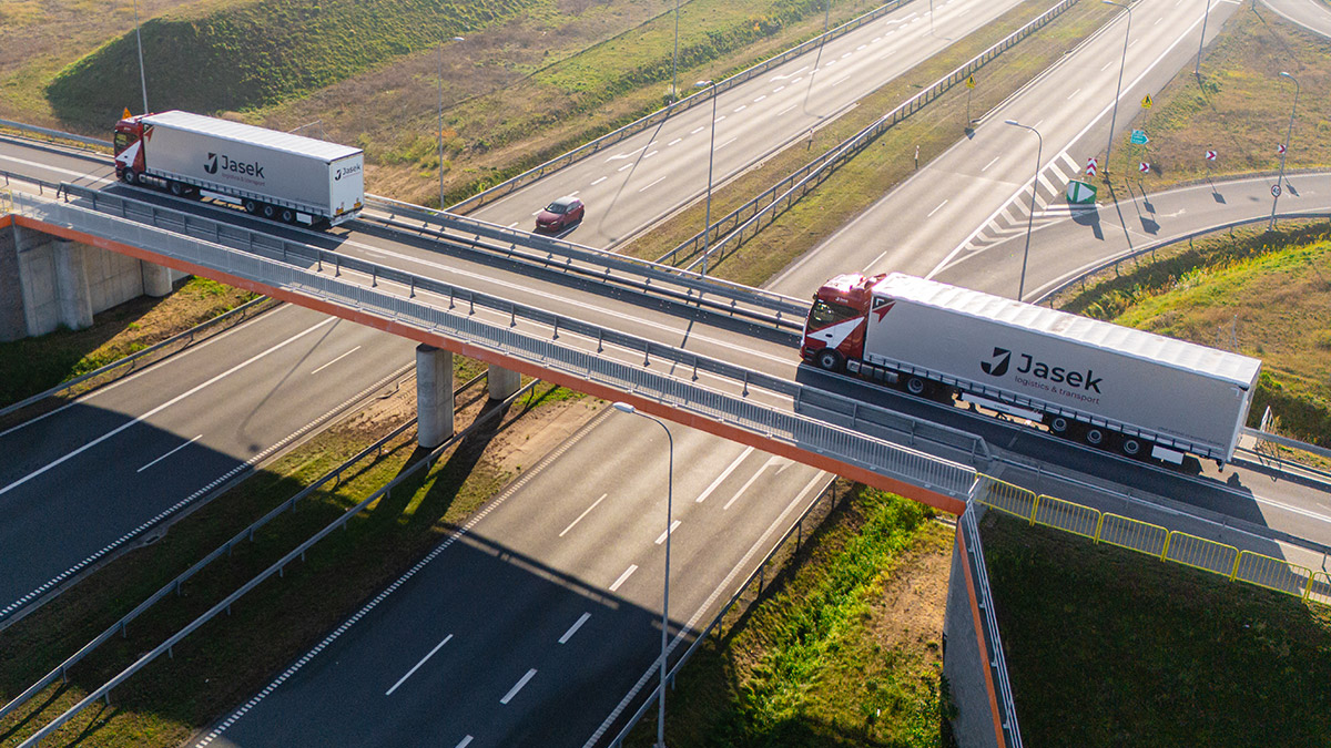 Dwa auta ciężarowe na wiadukcie drogowym.