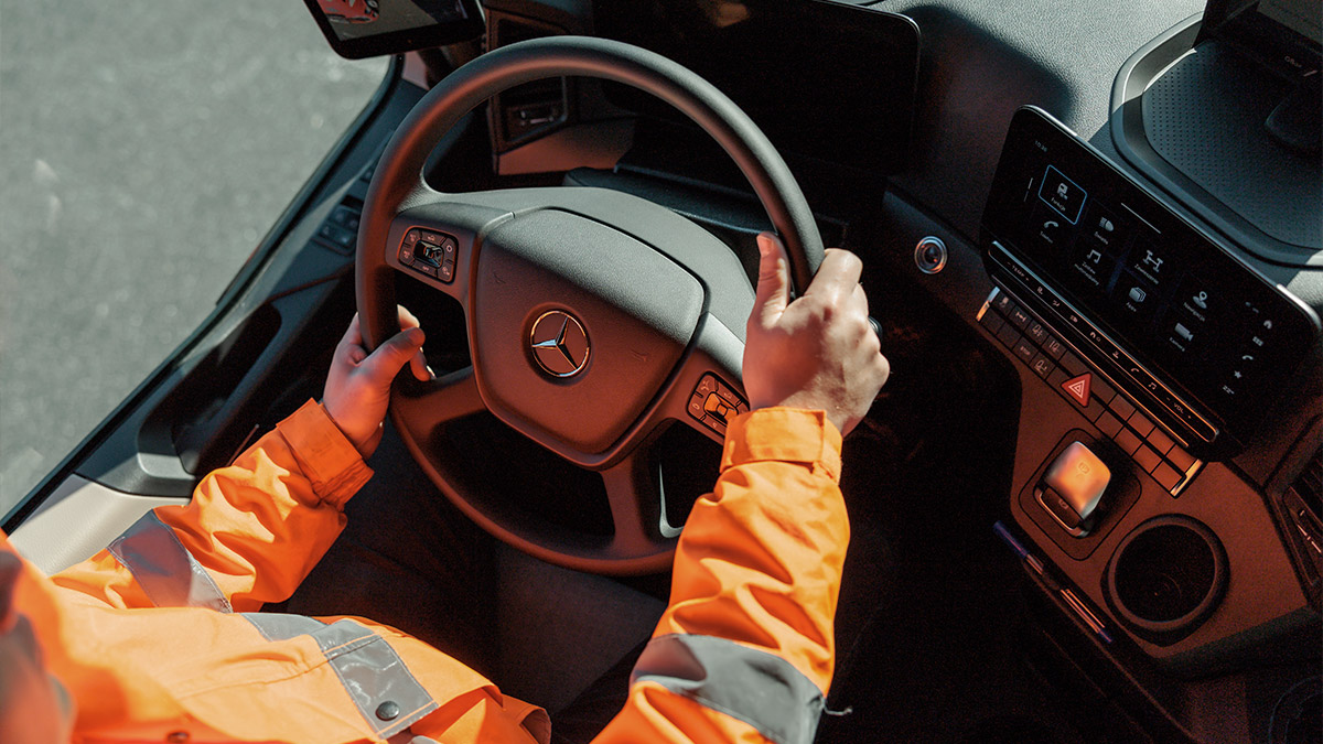 Dłonie mężczyzny trzymającego kierownicę auta ciężarowego.