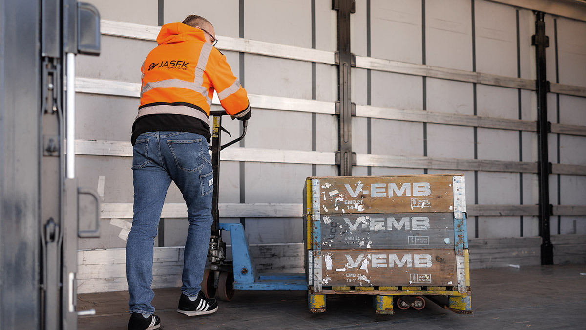 Mężczyzna ładujący paletę na naczepę auta ciężarowego.